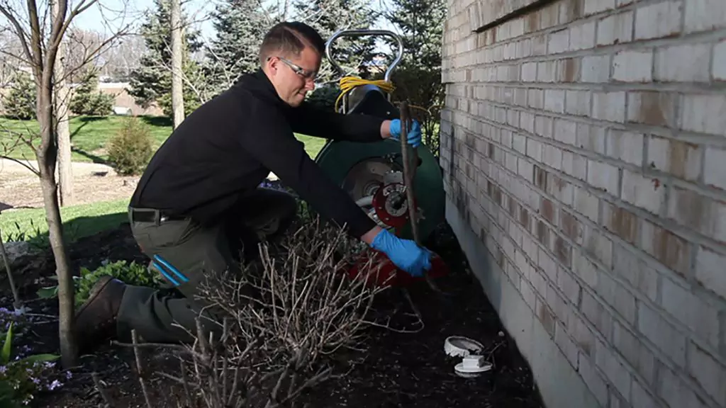 Man cleaning pipes outside of a house