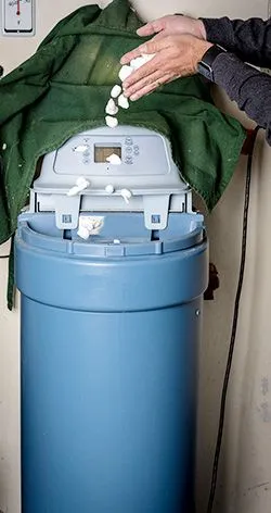 Person adding tablets into a water softener