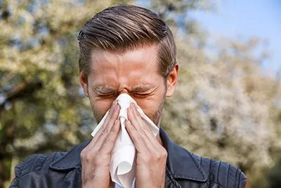 Man blowing his nose into a tissue