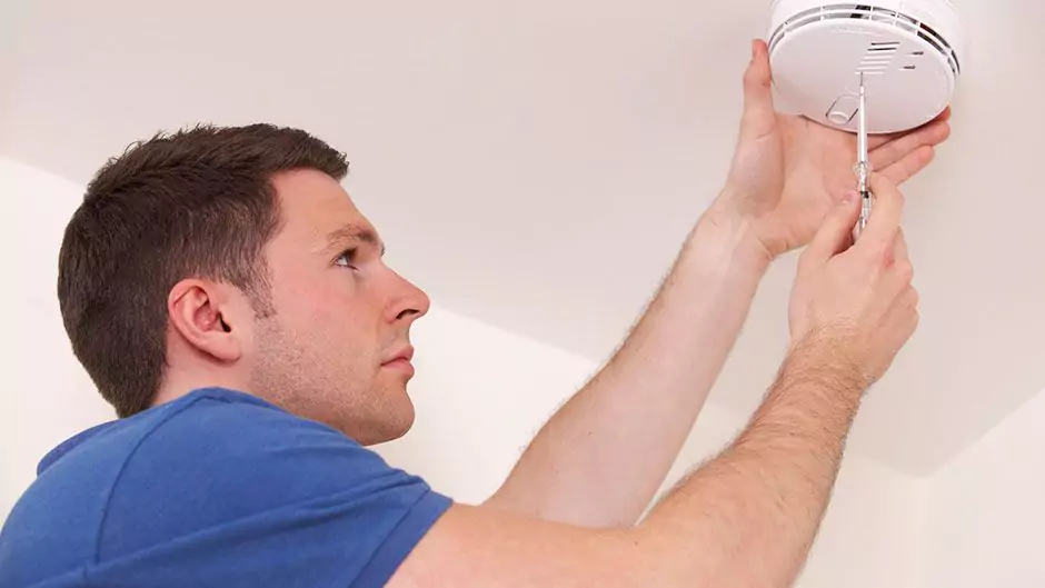 man fixing carbon monoxide detector