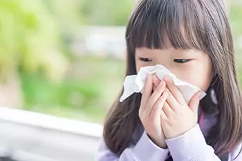 Little girl blowing her nose outside