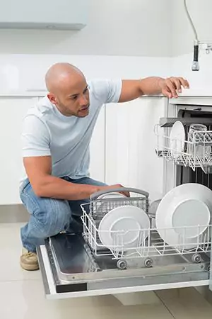 man inspecting his dishwasher