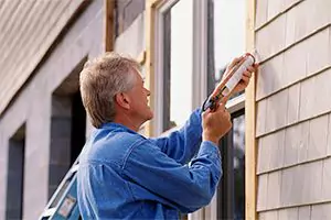 man outside a house fixing a leak