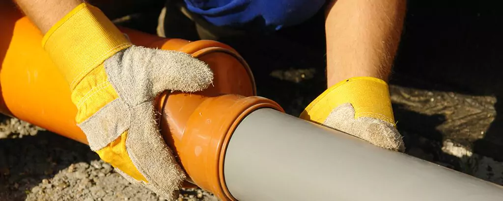 man replacing a pipe in the dirt