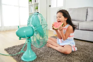 little girl eating watermelon in front of a fan